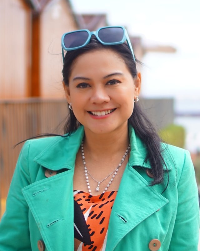 Nuniek Tirta Sari holding a cup of coffee by a window